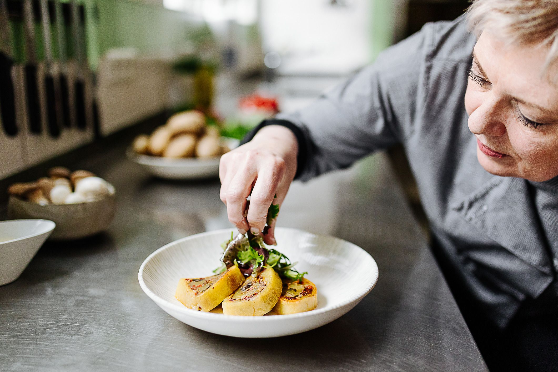 A woman arranges food and salad on a plate.