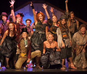 Theater group in colorful costumes on the stage of the Stadttheater Mödling.