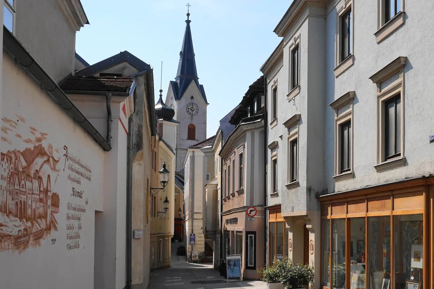 Narrow alley with old buildings and church tower in the background.
