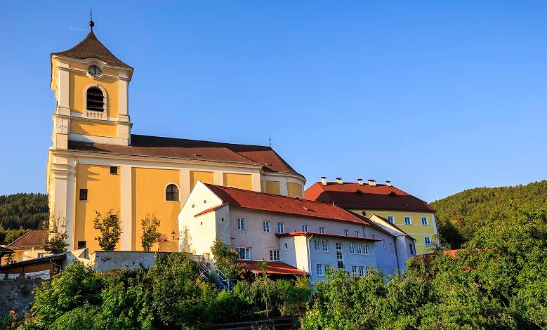 Parish church with adjoining monastery in a sunny landscape.