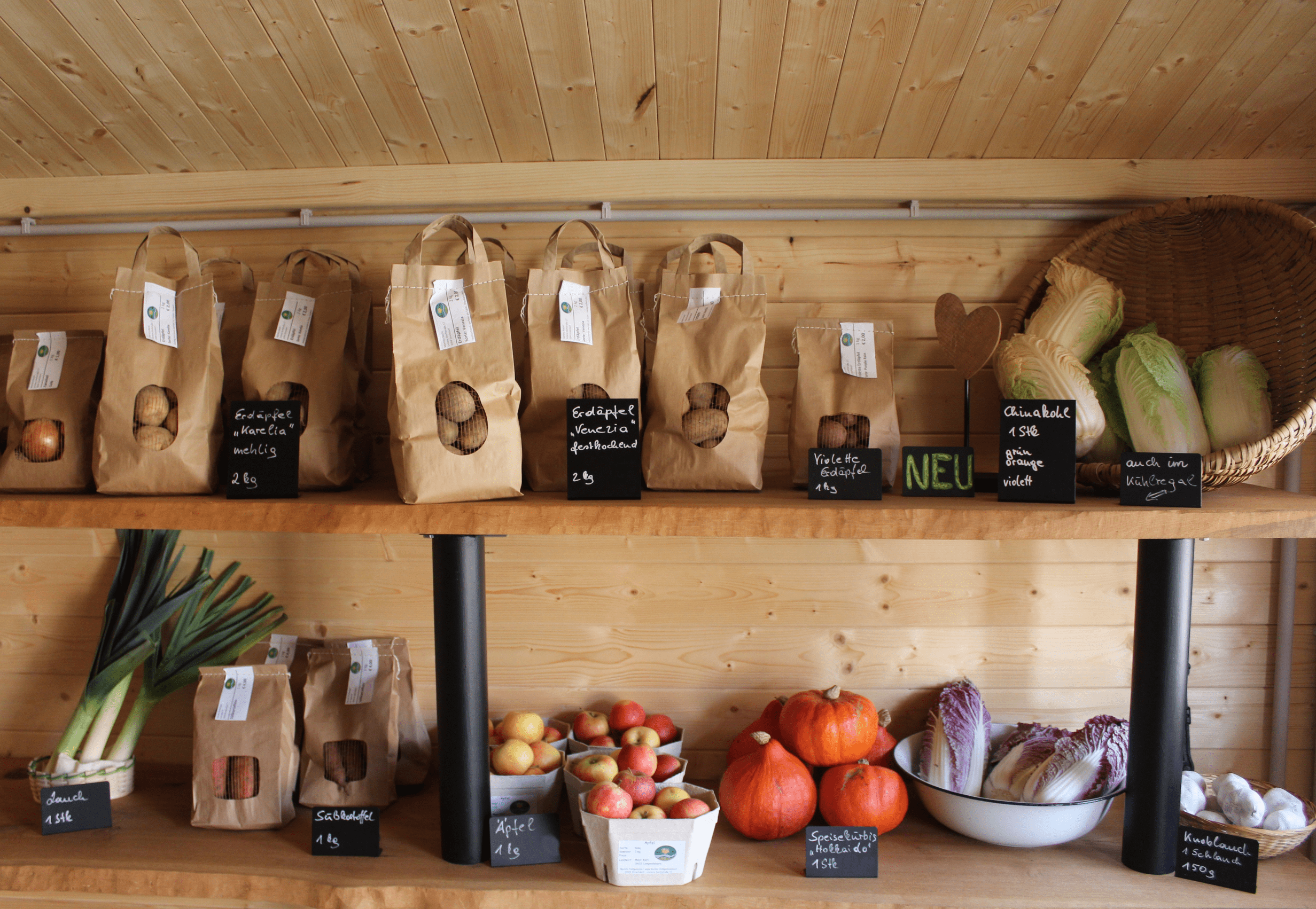 Shelf with potatoes, apples, pumpkins and vegetables in paper bags and baskets.