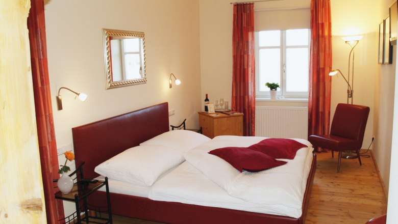 Cozy bedroom with red bed and decor.