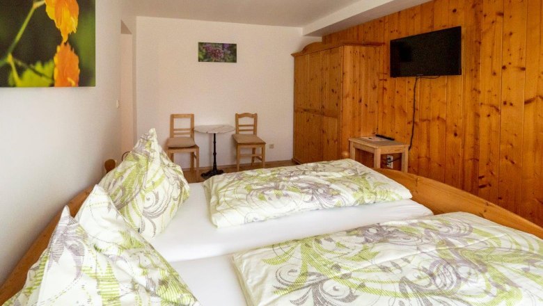Comfortable guest room with double bed, wooden furniture and TV.