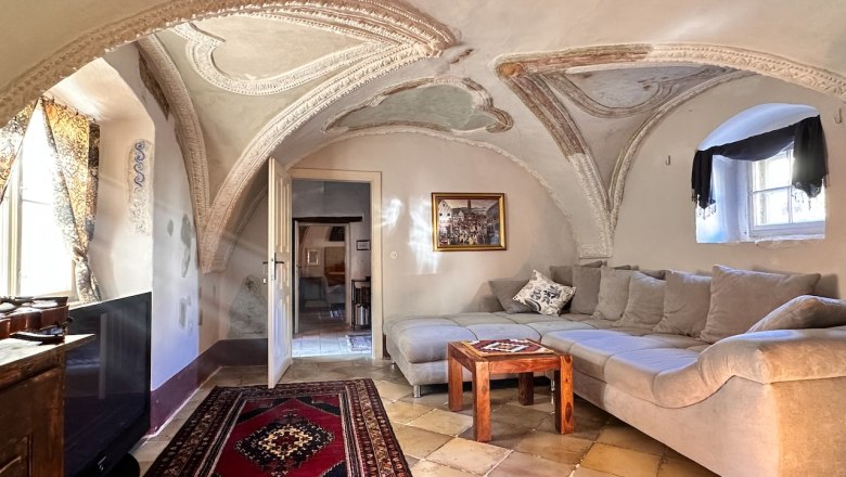 Historic room with vaulted ceiling, modern couch and carpet.