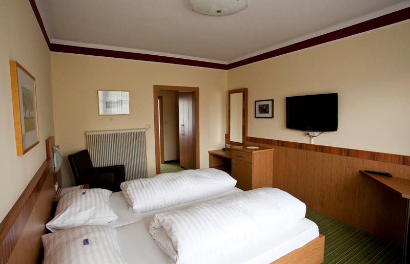 Hotel room with double bed, TV, desk and mirror.
