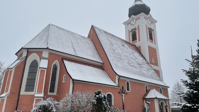 Gottsdorf parish church in winter with snow-covered roof and tower.