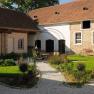 An idyllic inner courtyard with gravel paths, green plants and a seating area under a metal arch.