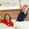Two children play happily in a bed in a guest room.