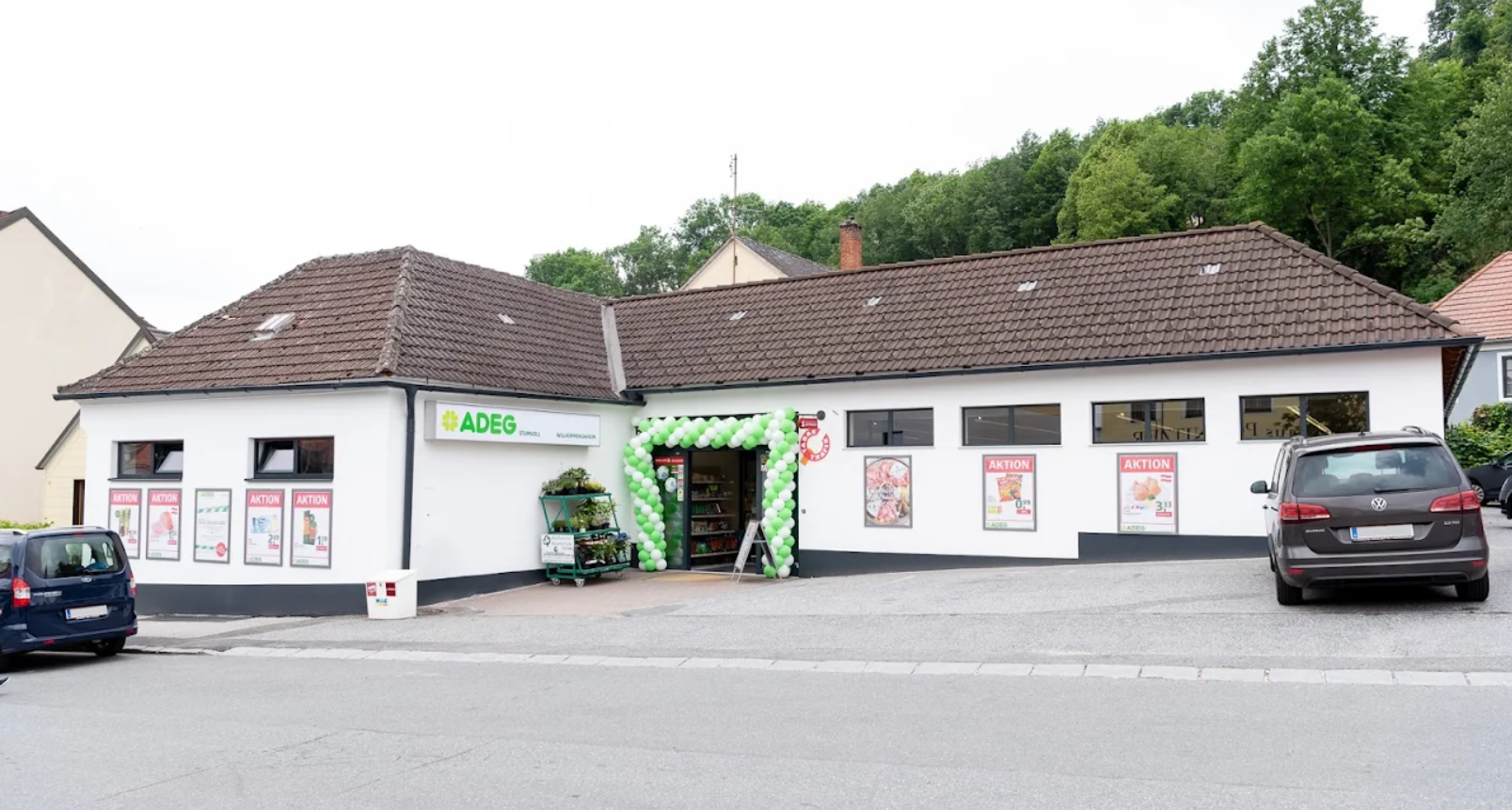 Entrance of an ADEG supermarket decorated with balloons.