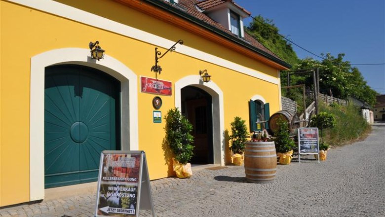 Yellow building with wine cellar and advertising boards in front of it.
