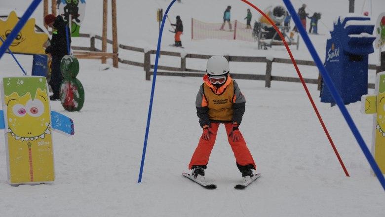 A child in ski equipment passes through an archway at the Semmering ski school.