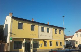 Yellow building with the inscription 'Andis Gästezimmer' and 'Cafe'.