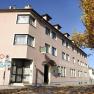 Exterior view of the Hotel Osterbauer with pink façade and autumn leaves on the ground.