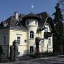 Exterior view of a yellow villa with turret and balcony.