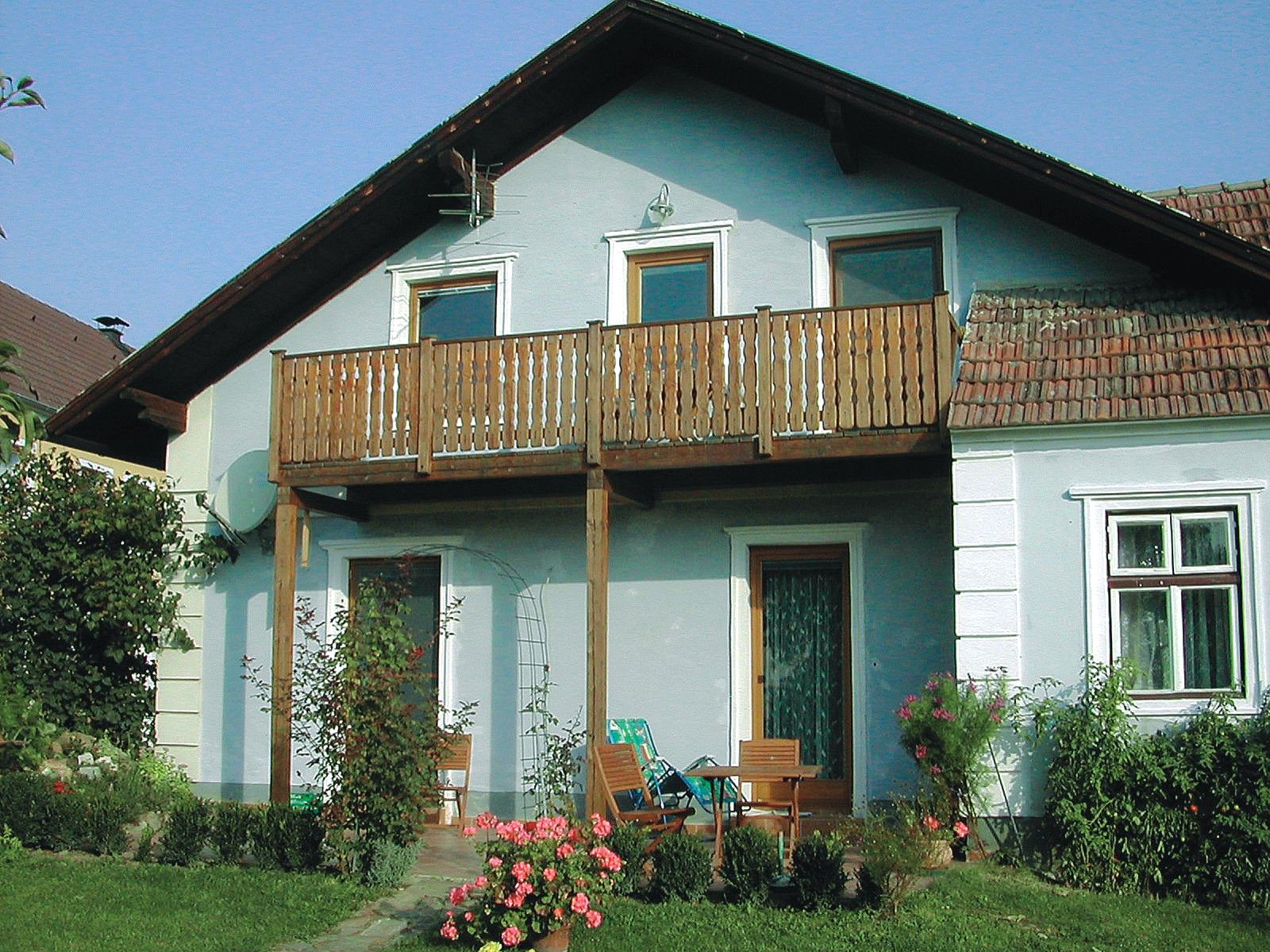 A traditional winegrower's house with a wooden balcony and garden furniture in front of the door.