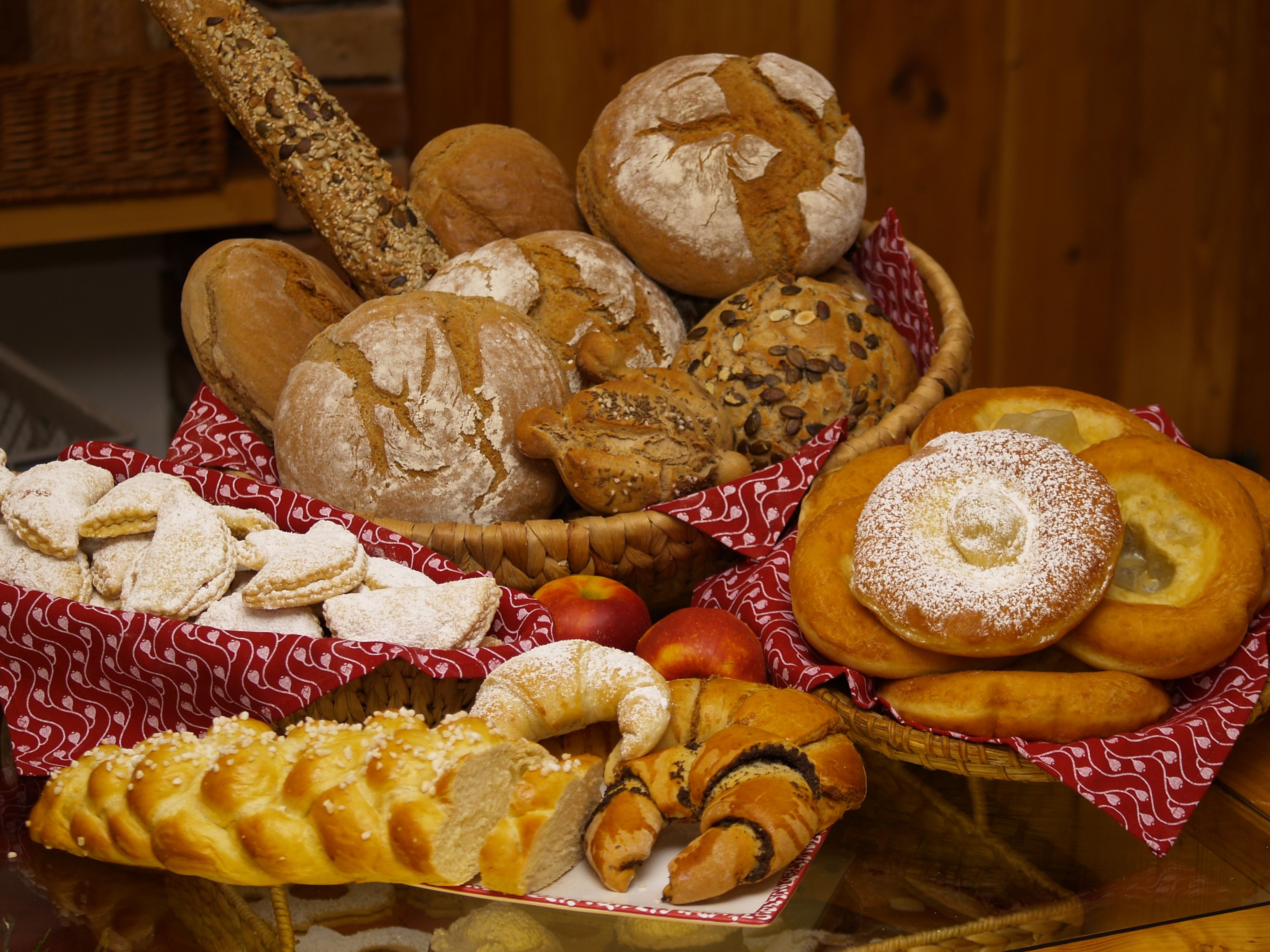 Various breads and pastries on a table, decorated with red cloths.