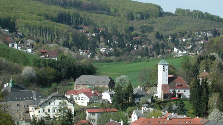 Panorama of Gablitz with church and surrounding houses in front of wooded hills.