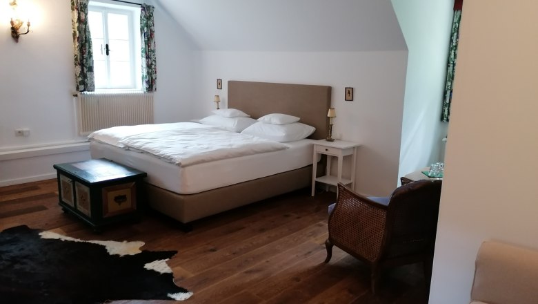 Cozy bedroom with double bed, wooden floor, carpet and antique furniture.
