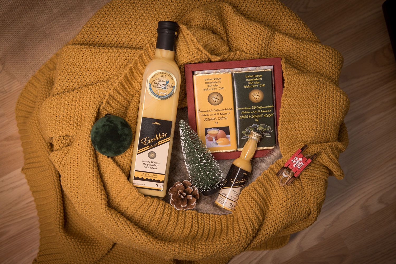 Gift set with egg liqueur, chocolate and decoration on yellow knitted fabric.