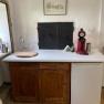 Small kitchen with wooden cupboards, white worktop, red coffee machine and small fridge.