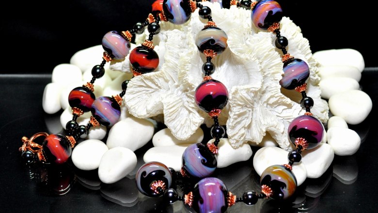 Colorful pearl necklace on white stones and shell.