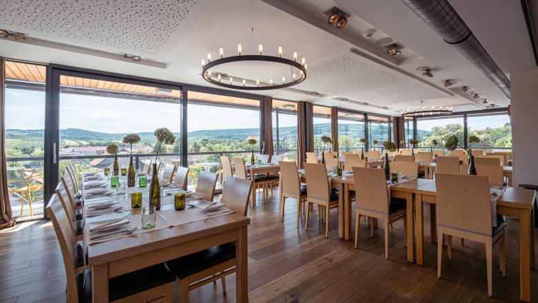 Interior view of a modern restaurant with large windows and a view of vineyards.