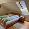 Cozy double room with skylight, wooden bed and bedside table.