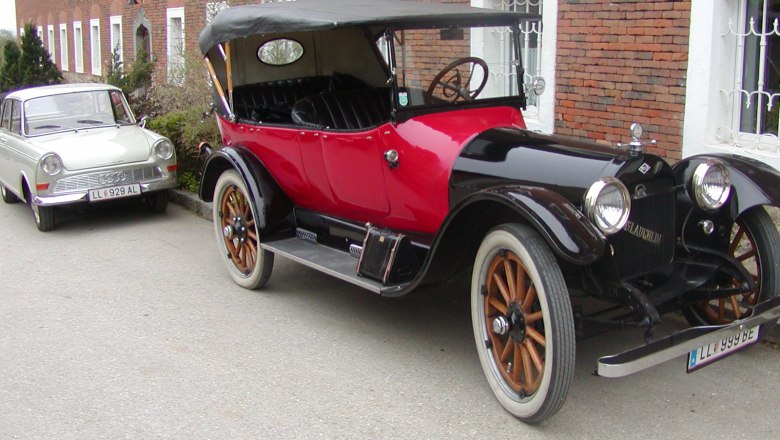 Two vintage cars parked in front of a brick building.