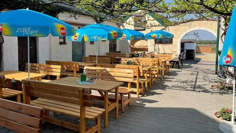 A sunny guest garden with wooden benches and blue parasols.