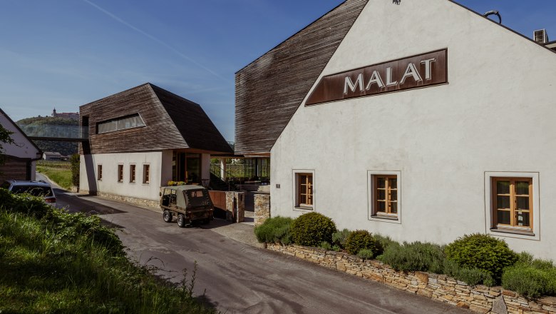 MALAT Winery and Hotel, © Niederösterreich Werbung / Maximilian Pawlikowsky Exterior view of the MALAT winery and hotel with modern architecture and a vehicle in the foreground.