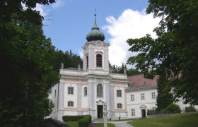 Baroque church on the Mariahilfberg with a green tower and surrounded by trees.