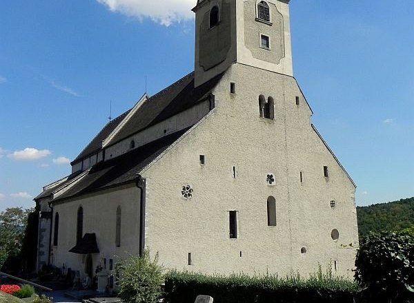 A historic church with a tower and surrounding cemetery under a clear sky.