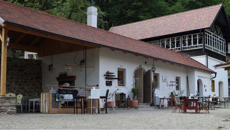 A traditional building with a red tiled roof and wooden elements, surrounded by trees.