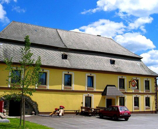 Yellow inn with gray roof and red car in front.
