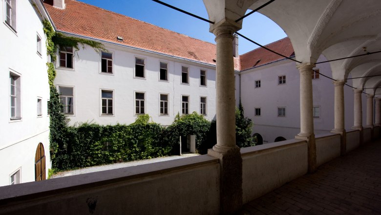Inner courtyard of a historic building with arcade and ivy-covered walls.