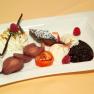A dessert plate with various desserts, including cream, berries, chocolate cake and poached pears.
