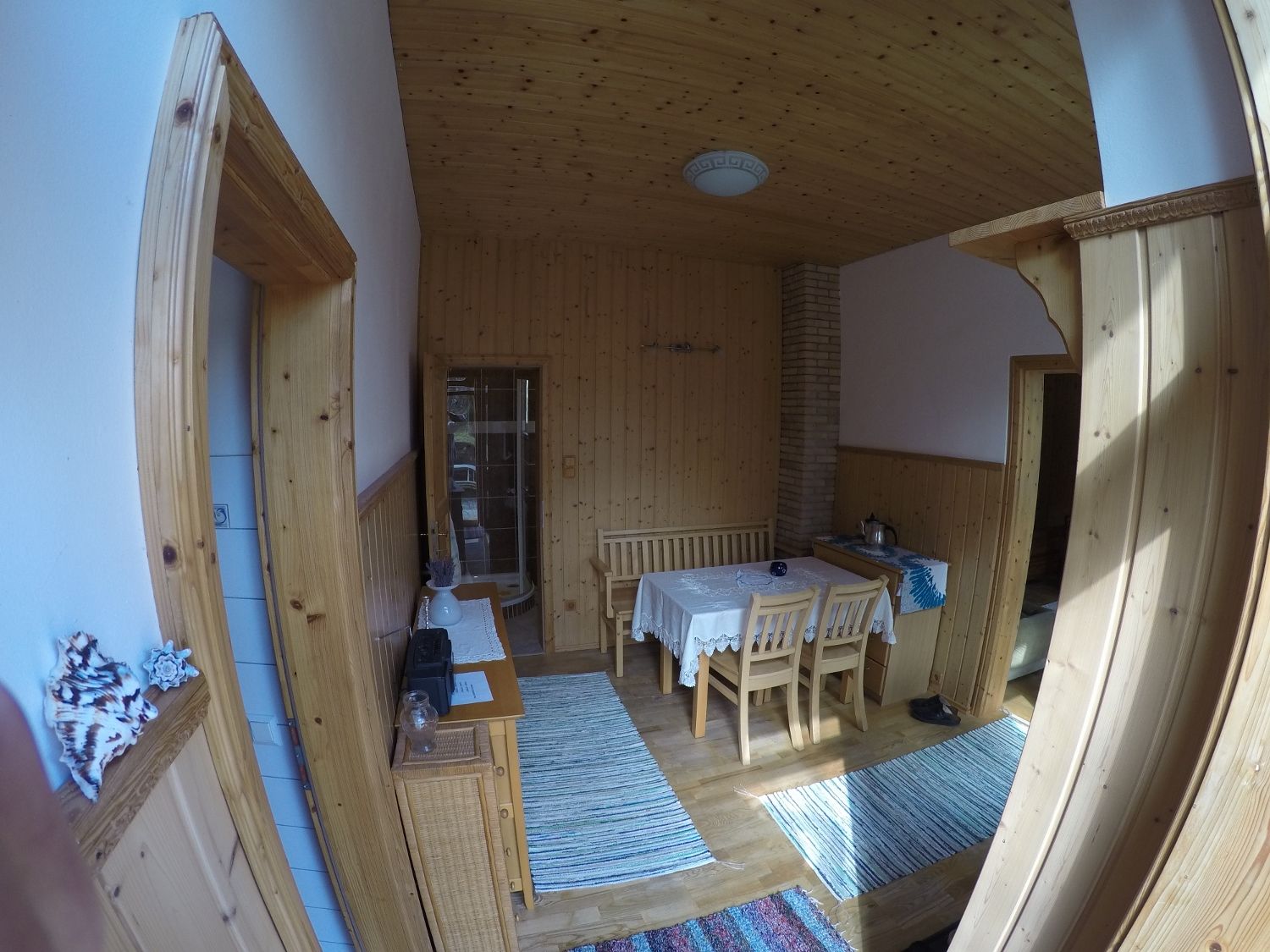 Dining room with wooden walls, table and chairs, carpets and decorations.