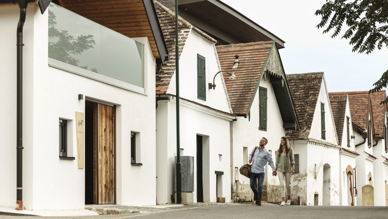 A couple strolls past traditional wine cellars.