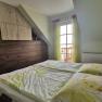 Bedroom with double bed, wooden wardrobe and window with yellow curtains.