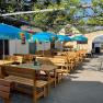 A sunny guest garden with wooden benches and blue parasols.