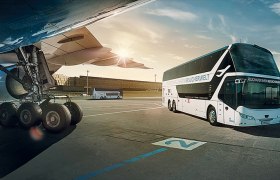 A bus stands next to an airplane on the tarmac at Vienna Airport.