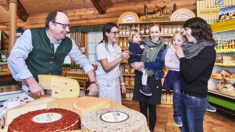 People in a cheese dairy, tasting cheese and smiling.