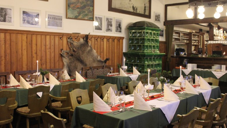 Cozy dining room with laid tables, wooden furniture and green tiled wall.