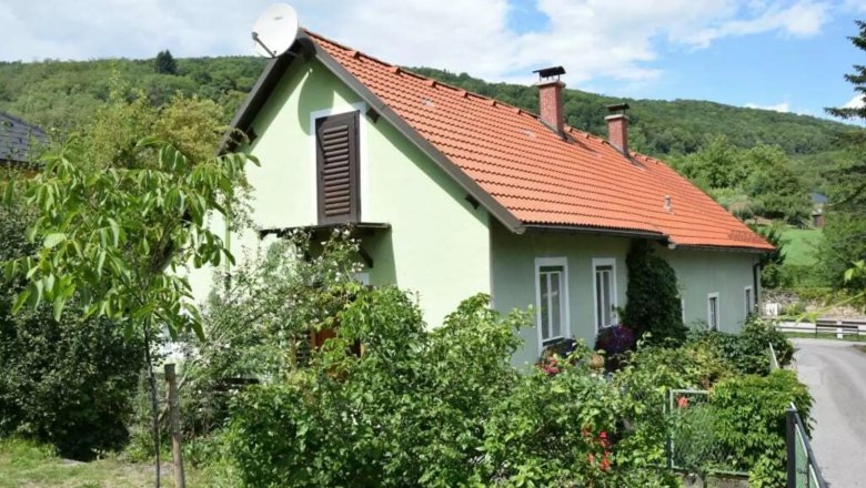 Green detached house from the outside with a red roof