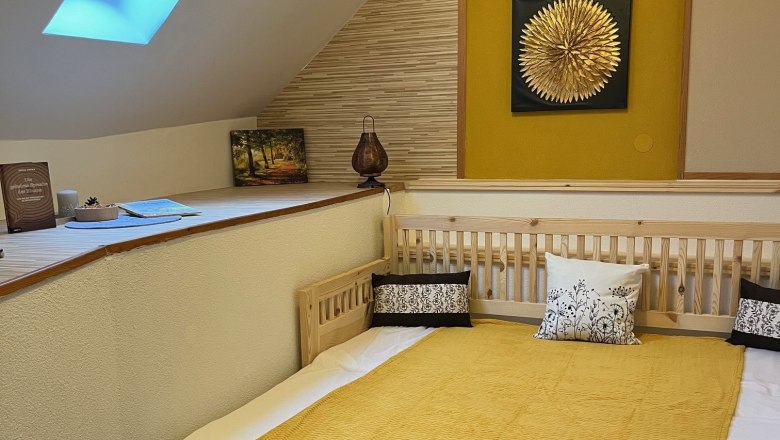 Cozy bedroom with skylight, yellow wall decoration and wooden bed.