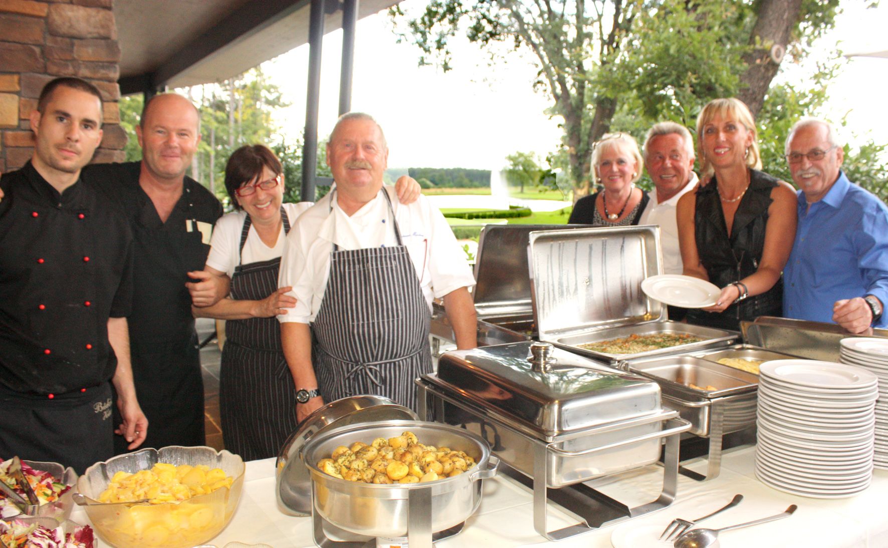Group of people in a restaurant next to a buffet of food.