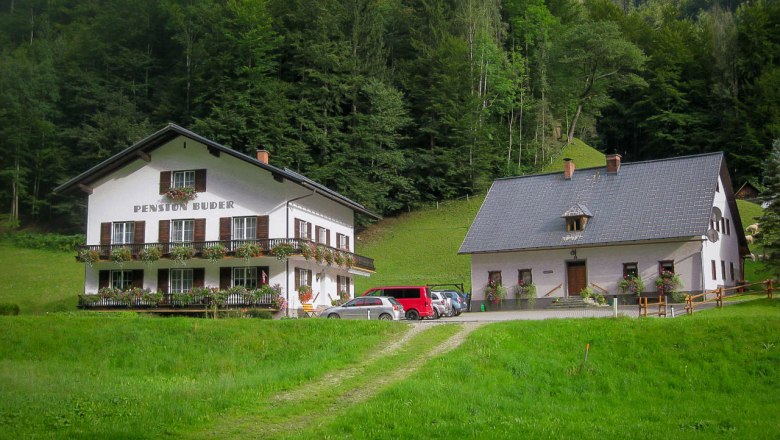 Two traditional buildings in a green, wooded setting.