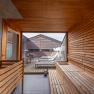 Interior view of a sauna overlooking a terrace with sun loungers and wooden walls.