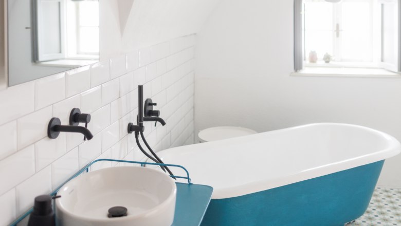 Modern bathroom with blue bathtub and washbasin.
