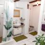 Modern bathroom with white tiles, green carpets and plant motif shower curtain.